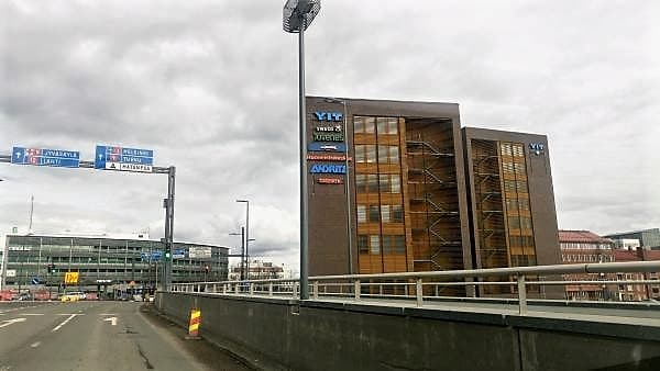 Näkymä kaupunkialueelta, jossa on tieopasteita ja toimistorakennus.