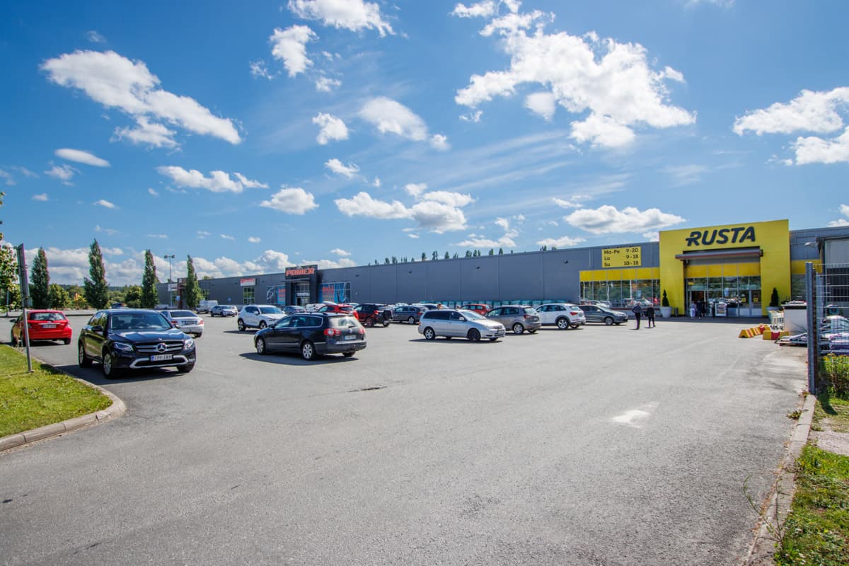 Liikekeskuksen parkkipaikka Rusta- ja Power-myymälöiden edustalla aurinkoisena päivänä.
