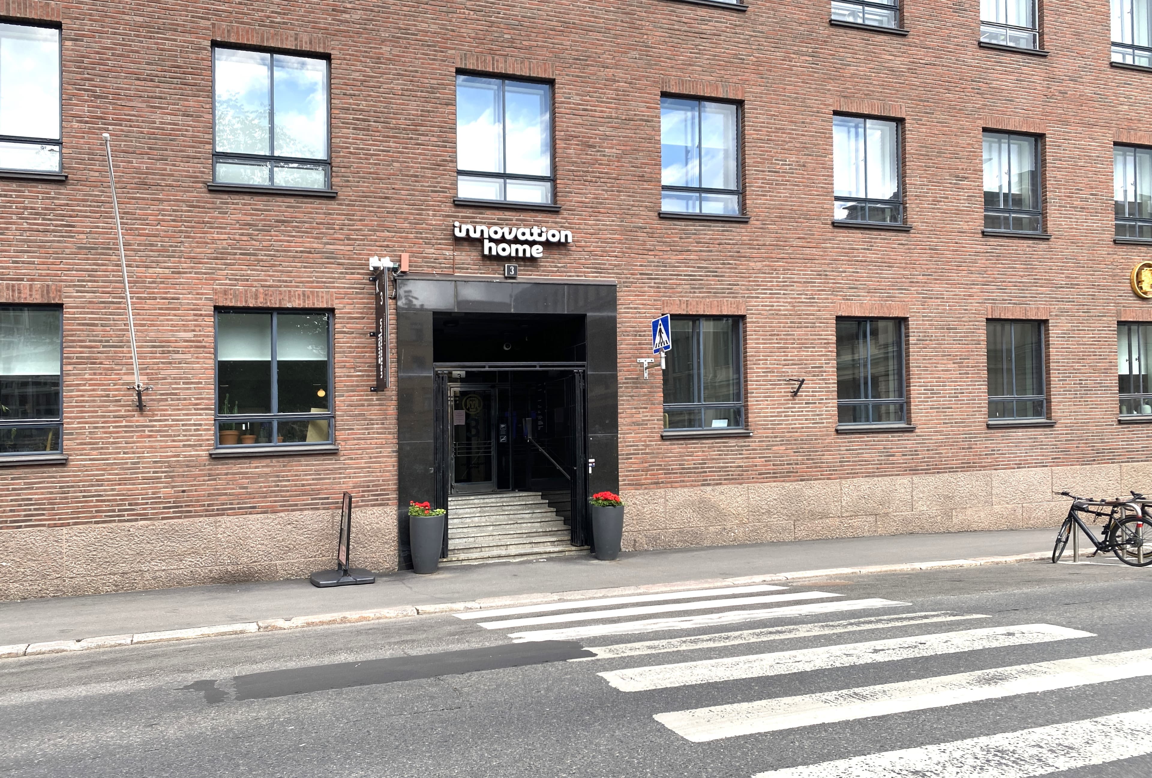 Punatiilisen rakennuksen julkisivu ja "innovation home" -sisäänkäynti suojatien äärellä.