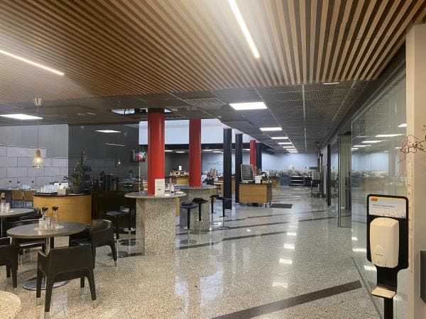 Moderni ja avara ravintolatila, jossa on erilaisia istumaryhmiä ja tyylikäs sisustus.
