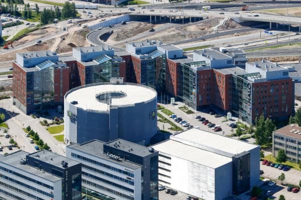 Ilmakuva modernista toimistoalueesta, jossa on useita rakennuksia, pyöreä pysäköintihalli ja taustalla moottoritieliittymä.
