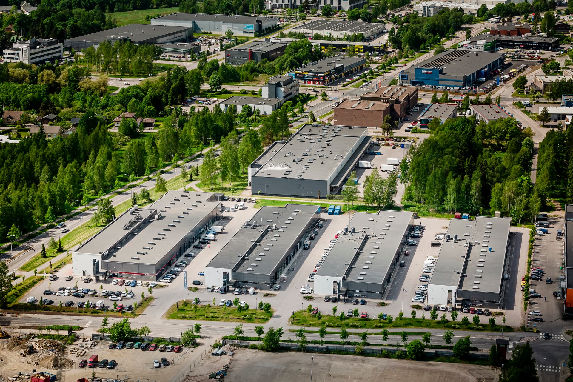 Ilmakuva teollisuus- ja liikealueesta, jossa on useita hallirakennuksia ja ympäröivää puustoa.