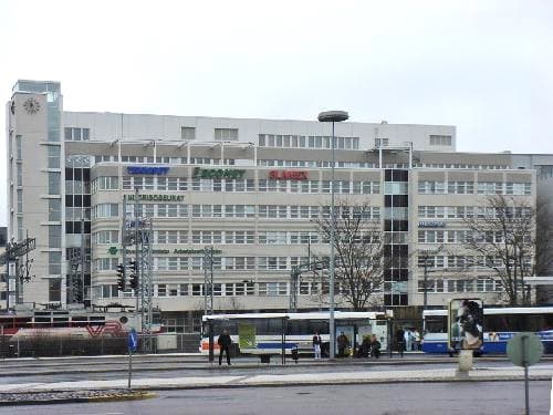 Monikerroksinen rakennus ja sen edustalla olevia linja-autoja.