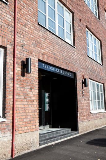 Punatiilisen rakennuksen sisäänkäynti, jonka yläpuolella on teksti Tekosilkkikutomo.