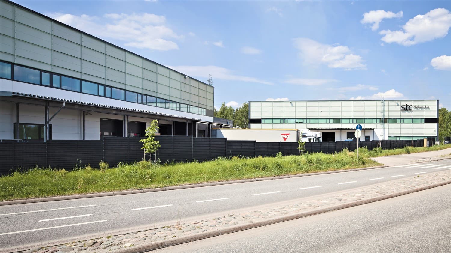 Moderni logistiikkakeskus ja teollisuusrakennuksia tien laidalla.