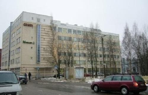 Vaalea monikerroksinen toimistorakennus ja autoja sen edessä.
