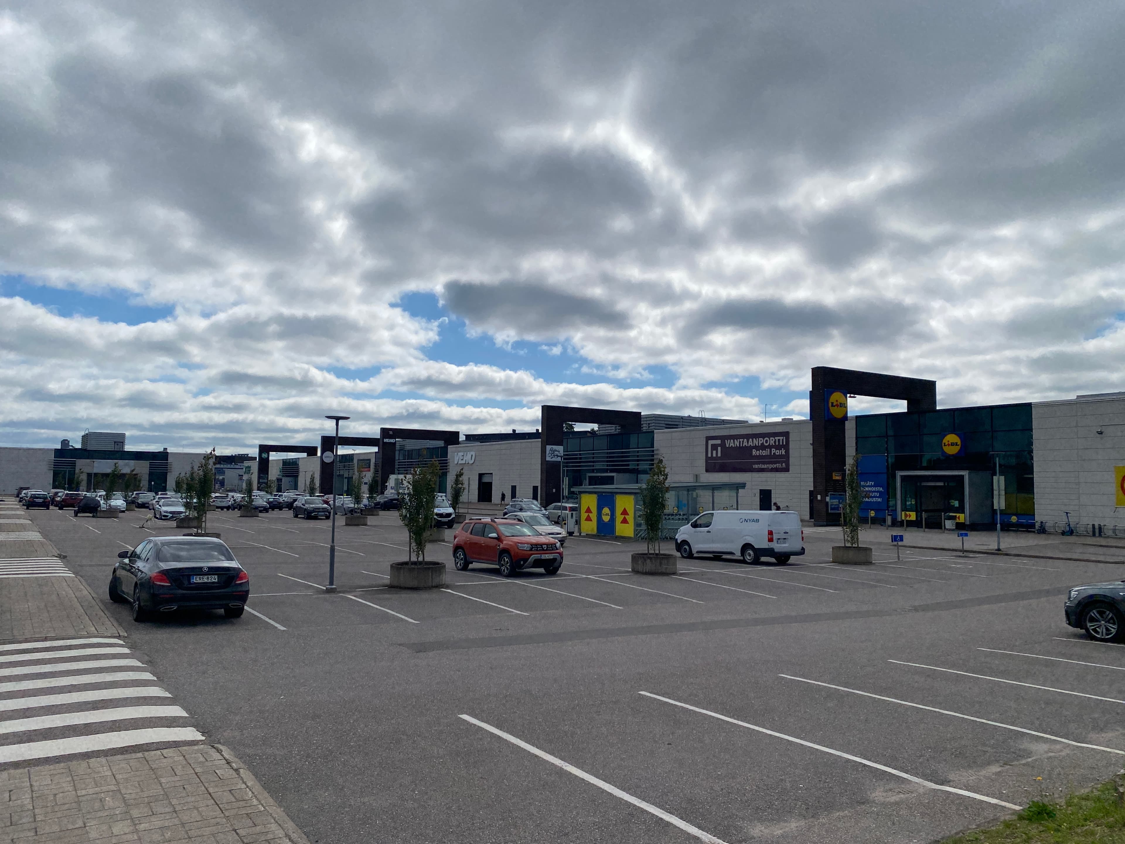 Vantaanportti Retail Parkin pysäköintialue ja liikerakennuksia pilvisenä päivänä.