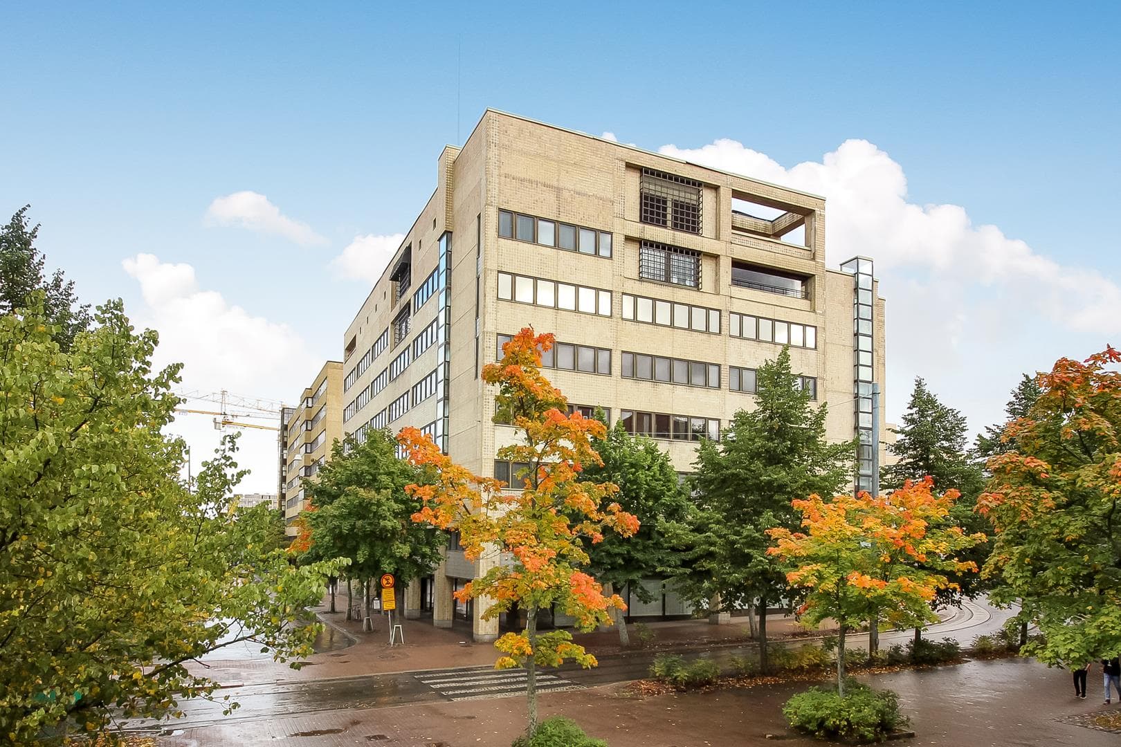 Vaalea rakennus syksyisessä kaupunkiympäristössä.