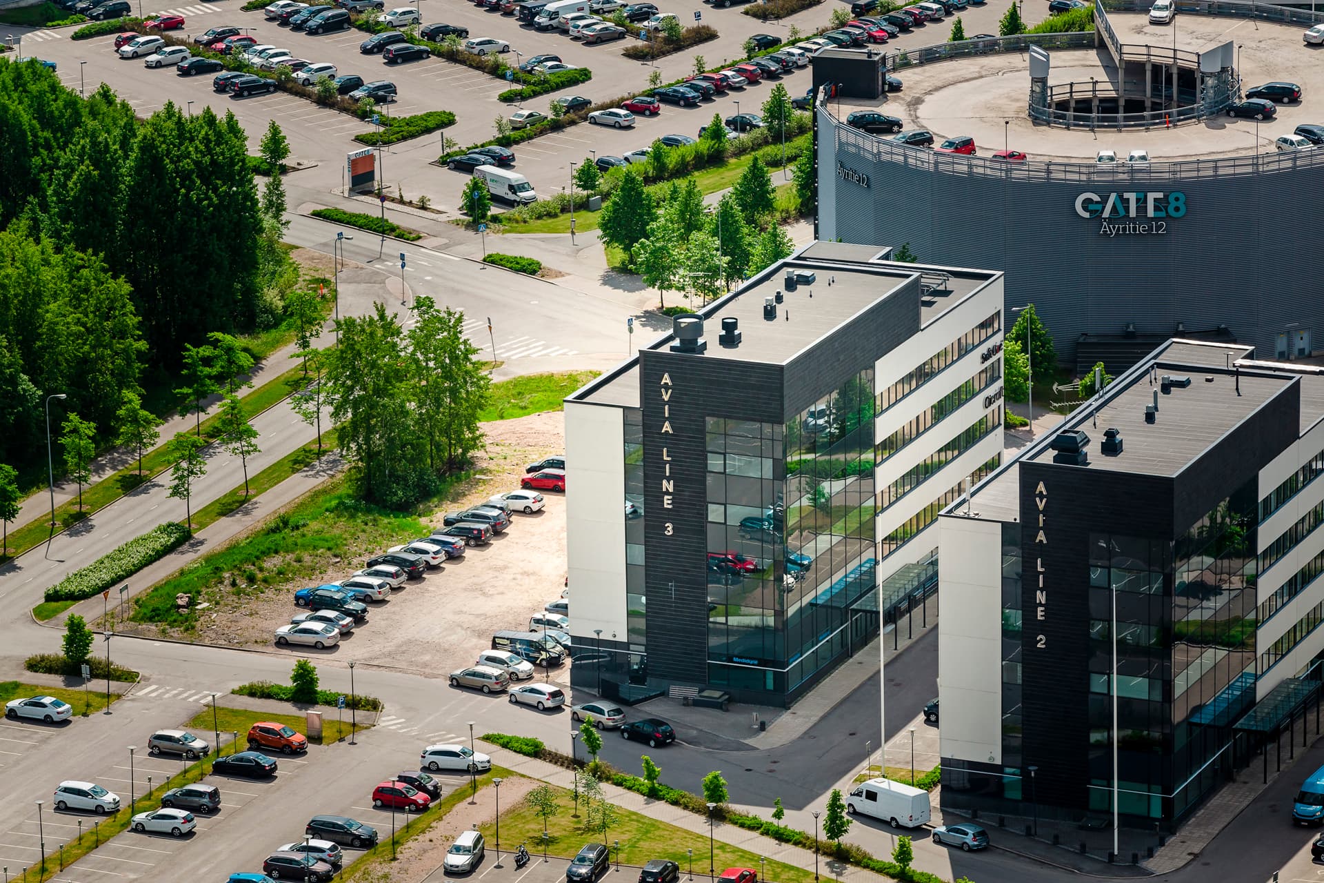Ilmakuva moderneista toimistorakennuksista ja laajoista pysäköintialueista.