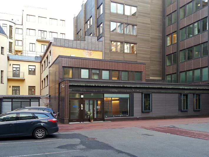 Näkymä rakennusten väliselle pihalle, jossa on pysäköity auto.