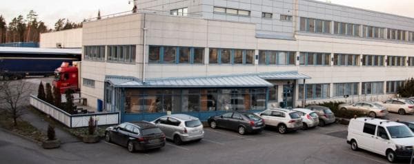 Monikerroksinen toimistorakennus ja parkkipaikka autoineen.