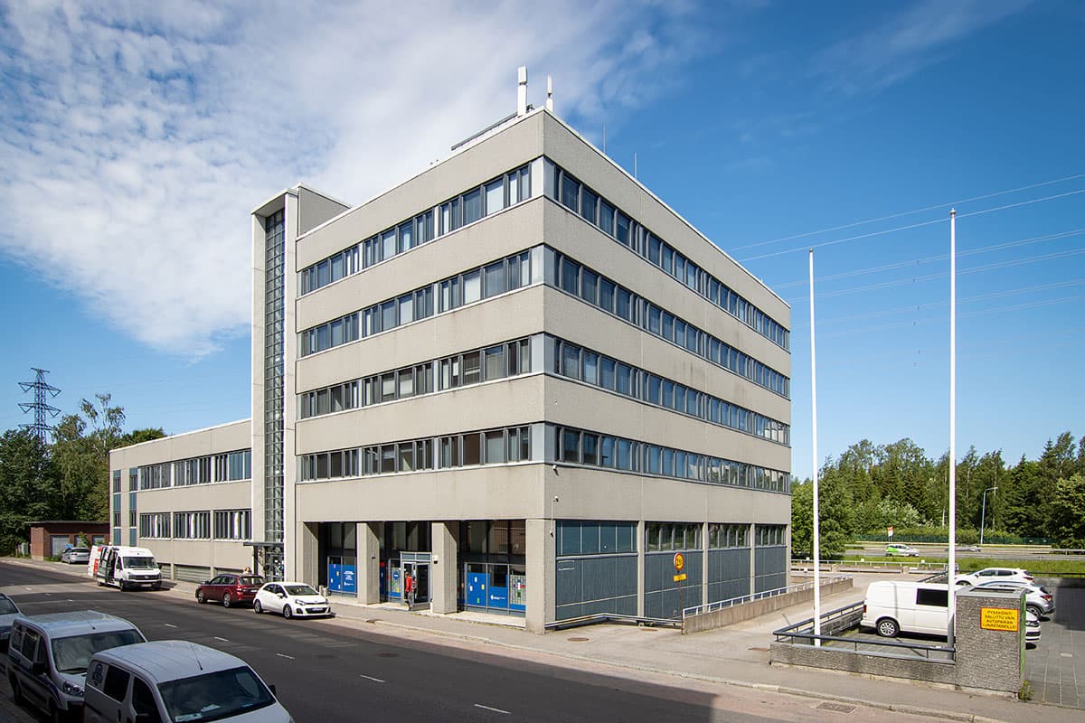 Harmaa monikerroksinen toimistorakennus kadun varrella.