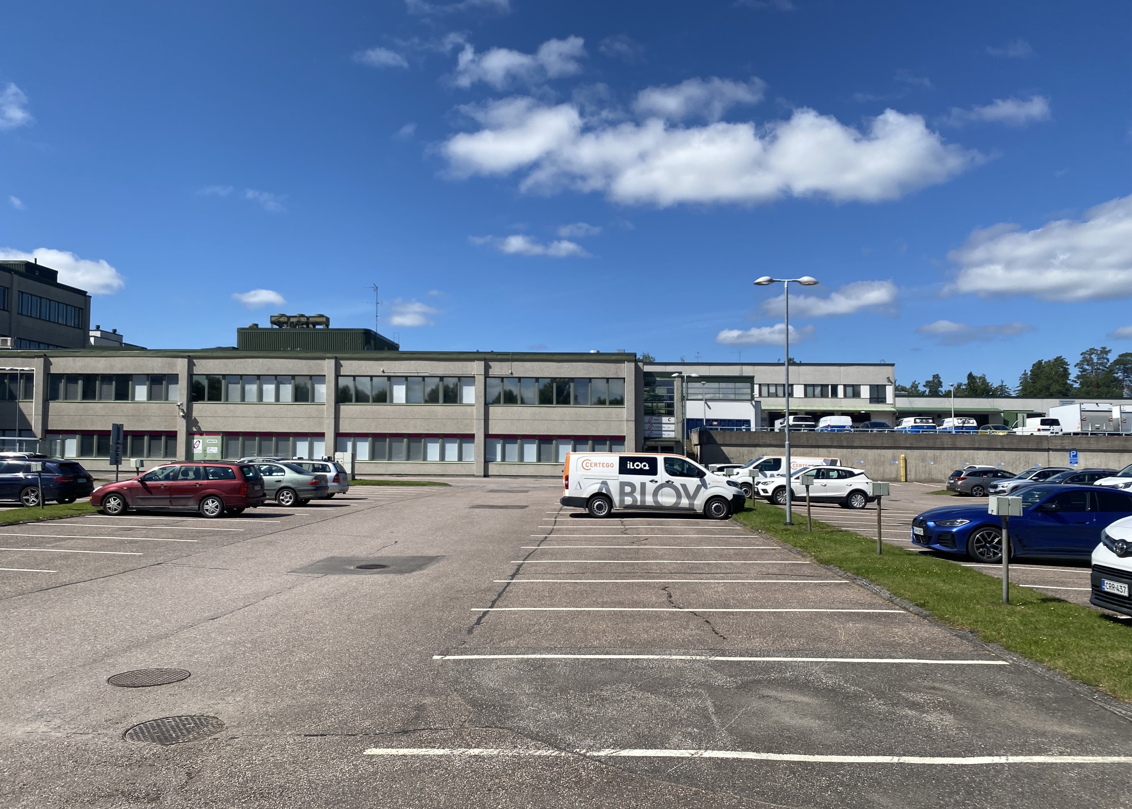 Pysäköintialue ja toimistorakennus aurinkoisena päivänä.