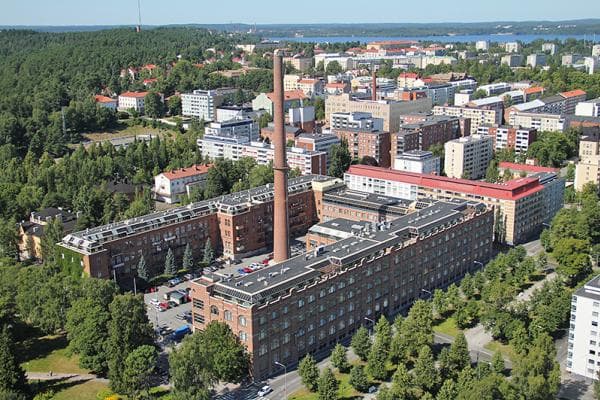 Ilmakuva kaupunkinäkymästä, jossa on punatiilinen rakennus korkeine savupiippuineen.