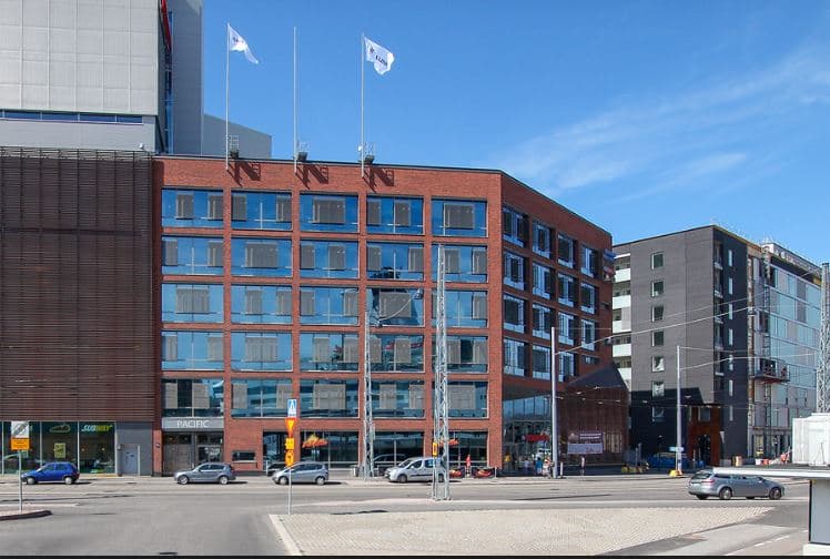 Moderni punatiilinen rakennus kaupunkikadun varrella.