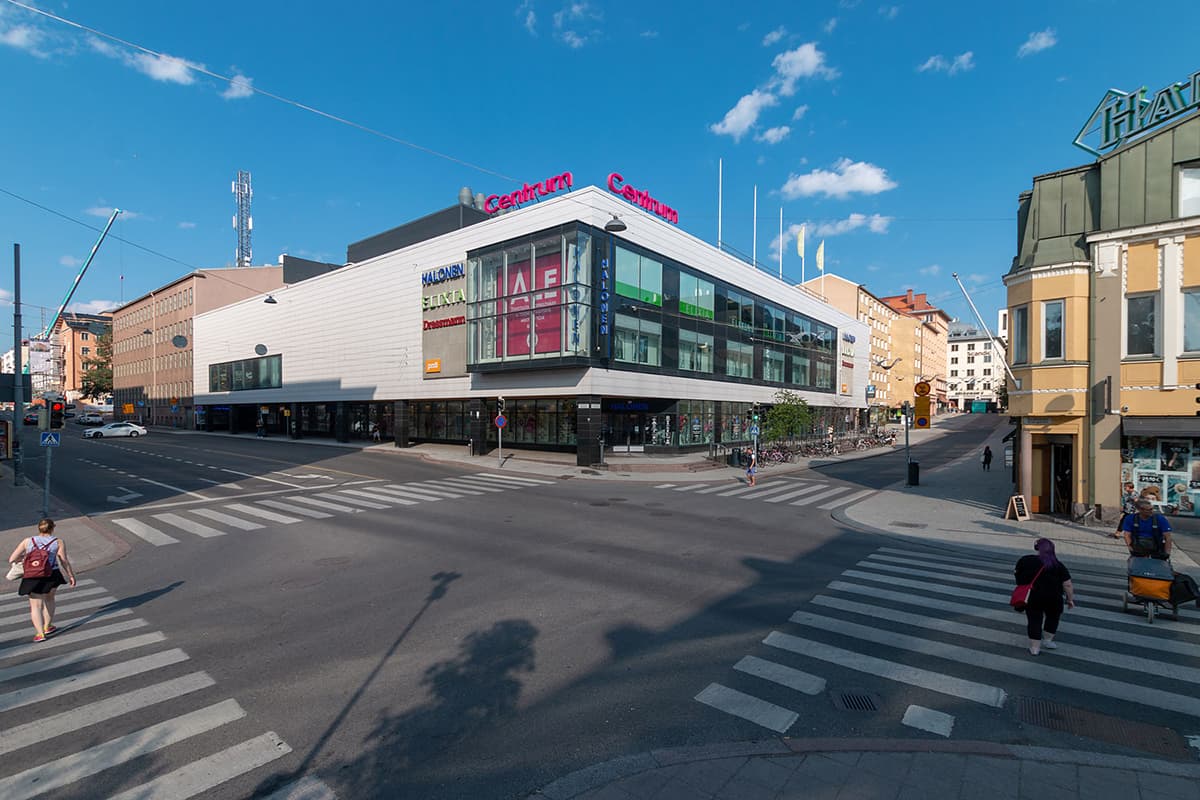 Katunäkymä, jossa on Centrum-kauppakeskus ja jalankulkijoita risteysalueella aurinkoisena päivänä.