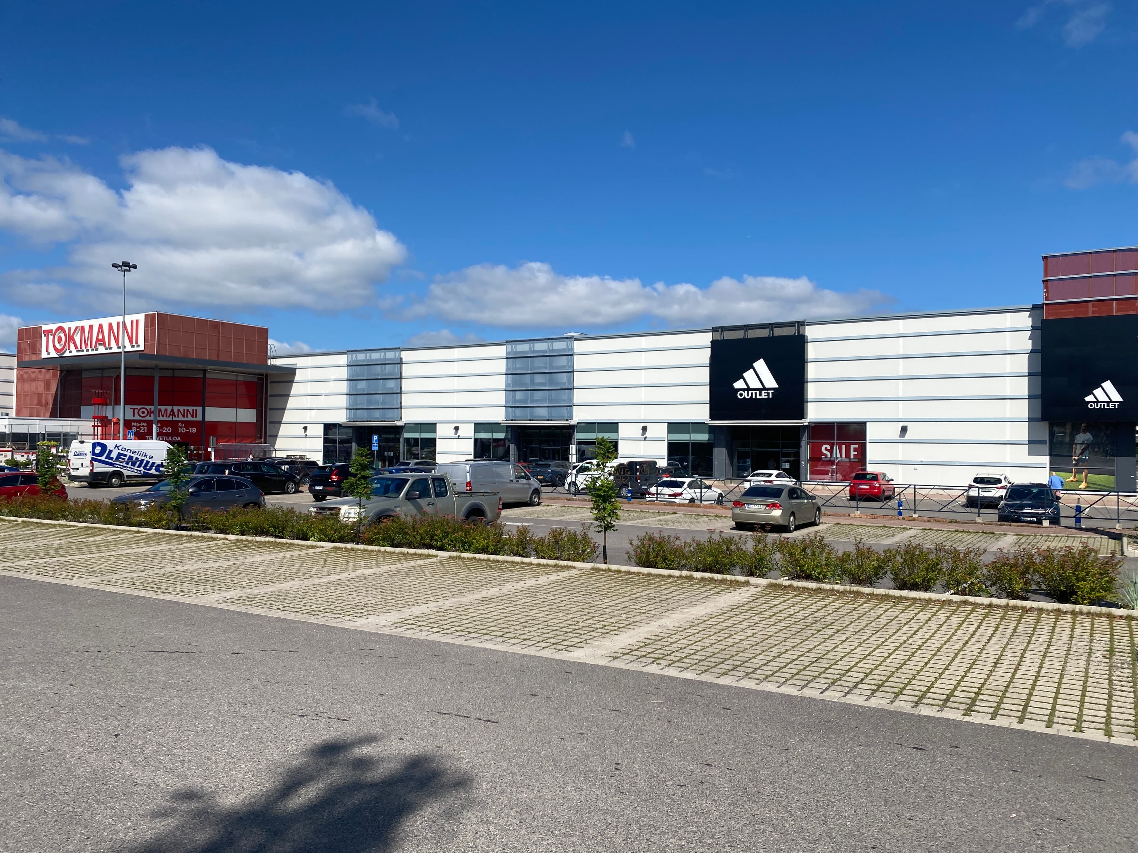 Näkymä ostoskeskuksen parkkipaikalta, jossa sijaitsevat Tokmanni ja Adidas Outlet -liikkeet.