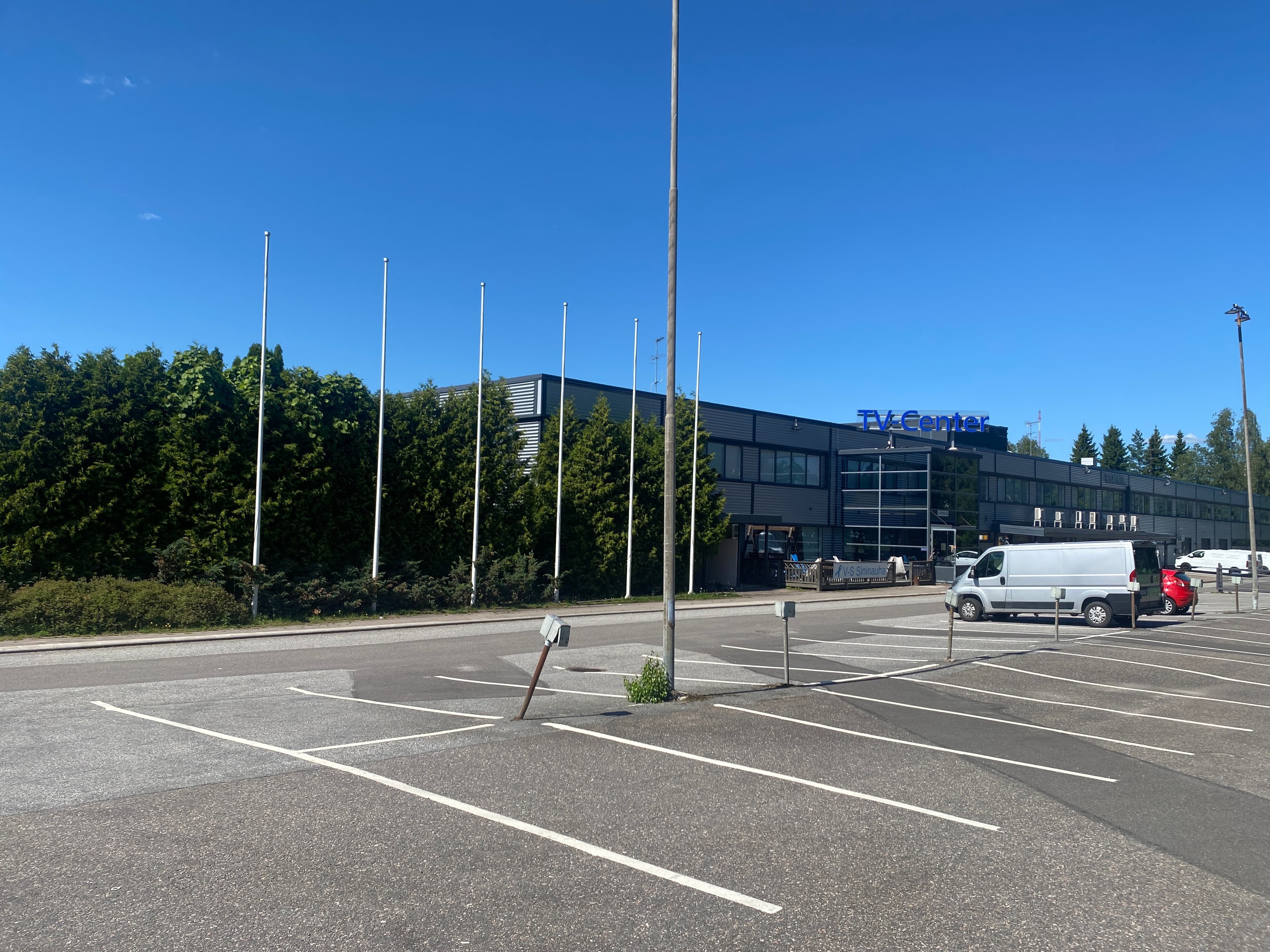 TV-Center-rakennus ja tyhjä pysäköintialue aurinkoisena päivänä.