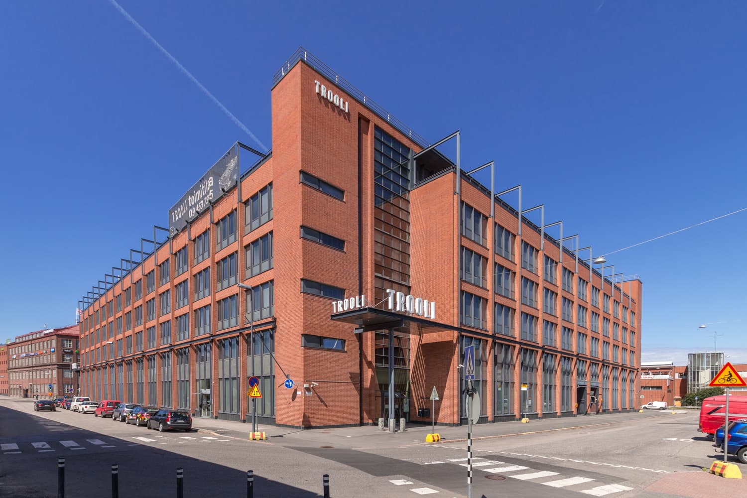 Punatiilinen Trooli-toimistorakennus kadunkulmassa aurinkoisena päivänä.