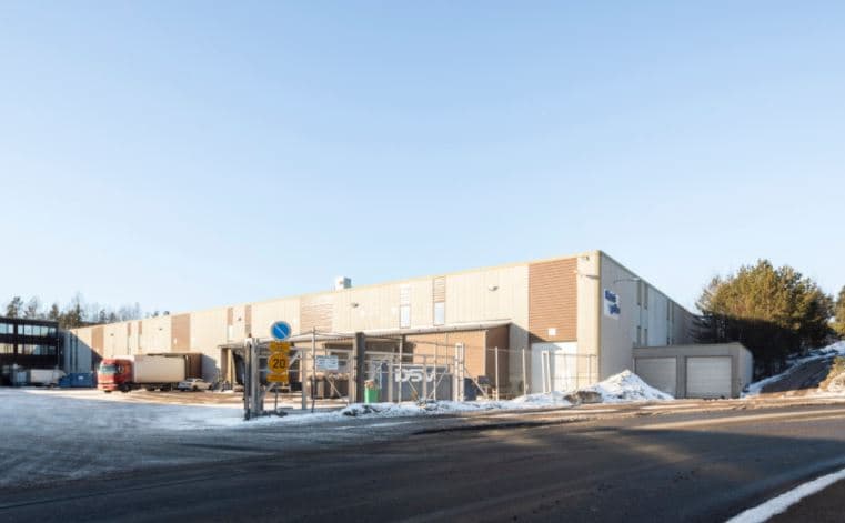 Teollisuusrakennus ja kuorma-auto lastauslaiturilla aurinkoisena talvipäivänä.