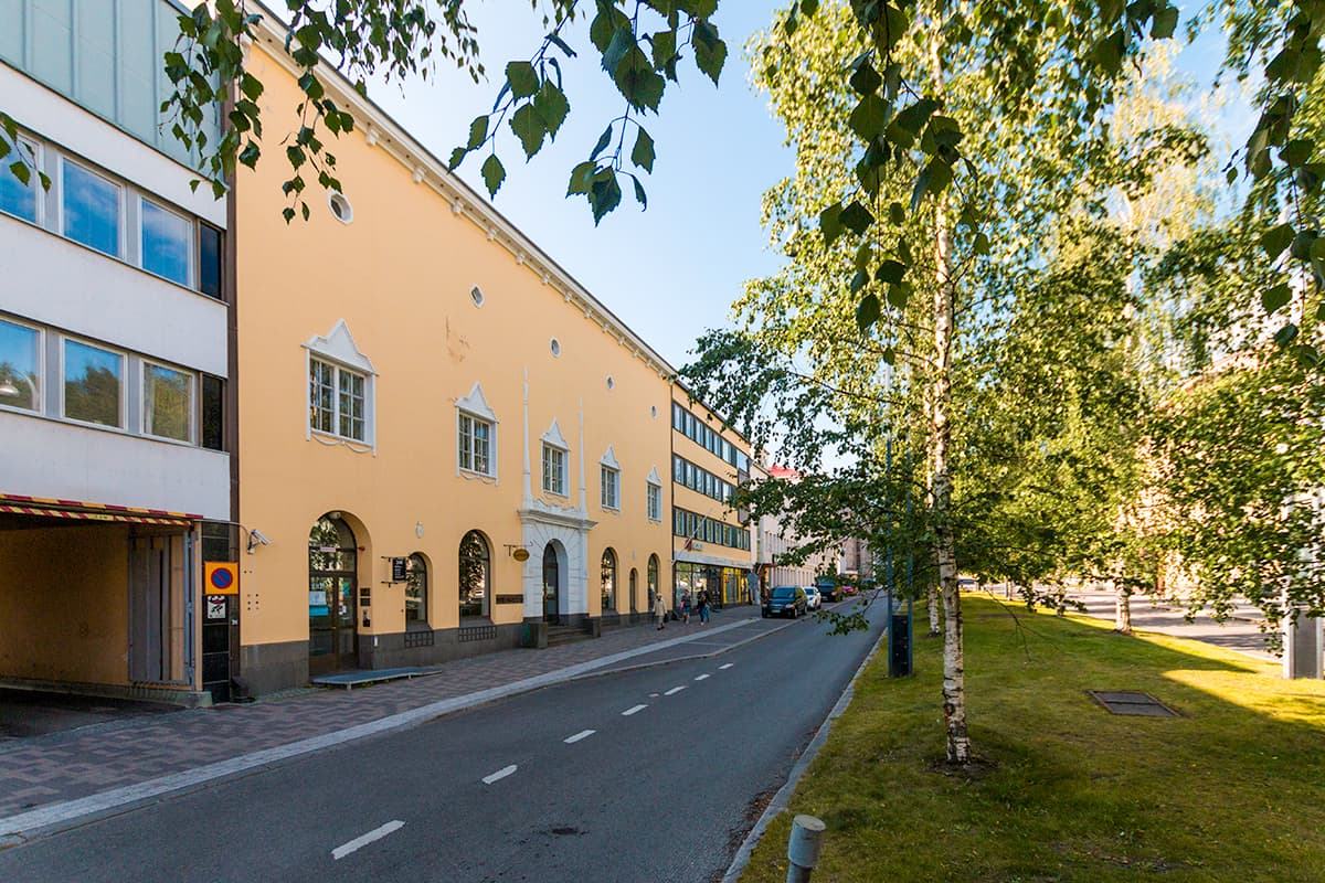 Aurinkoinen kaupunkinäkymä, jossa on keltaisia rakennuksia ja koivuja.